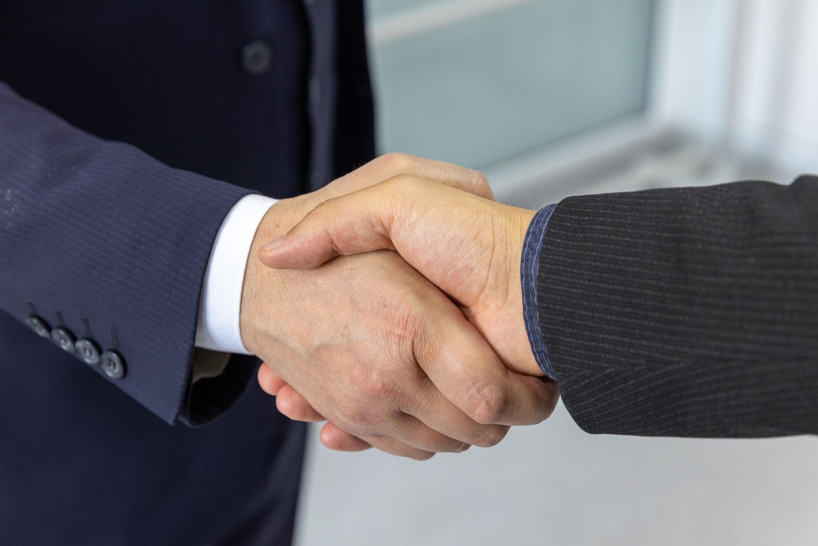 Two business professionals shaking hands, representing an Eye On Bits client partnership
